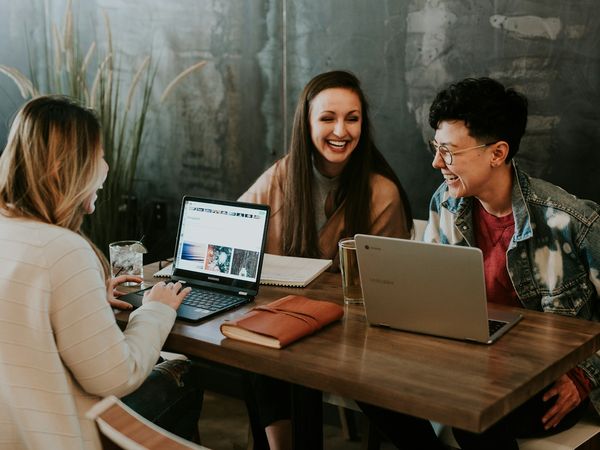 Three people talking over a laptop at a table